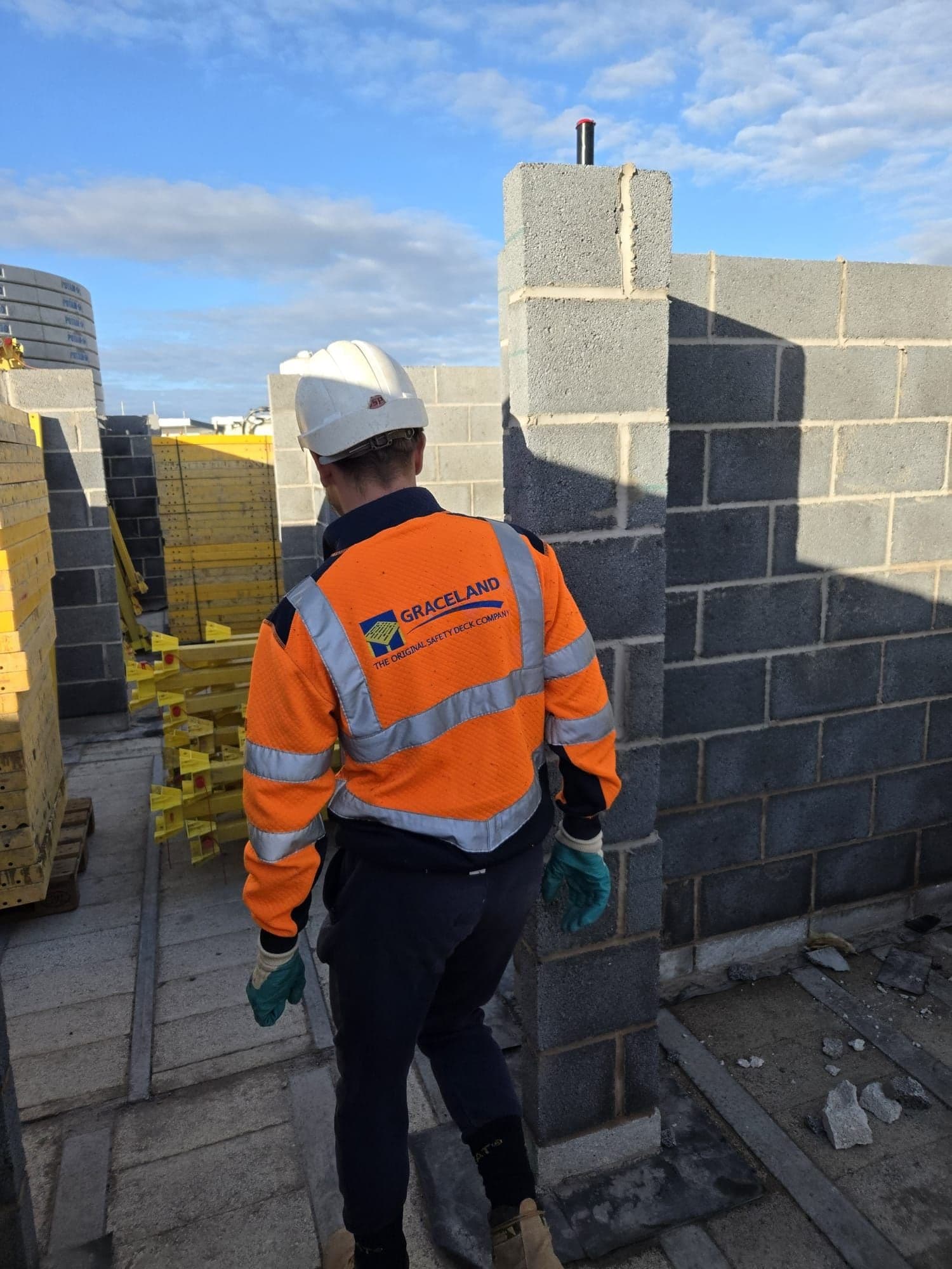 Graceland operative in branded hi-vis and hard hat on an upper floor of a block-built scheme